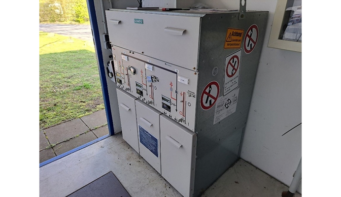 Elektrischer Schaltschrank in einem Technikraum mit Warnhinweisen und Bedienelementen.