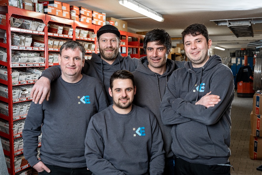 Fünf Mitarbeiter in einheitlichen Sweatshirts mit Firmenlogo